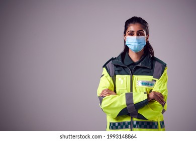 Studio Portrait Of Young Female Paramedic Wearing Face Mask Against Plain Background