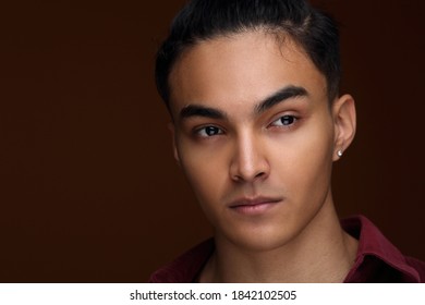 Studio portrait of a young handsome man of Asian appearance on a brown background