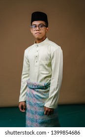 Studio Portrait Of A Young Malay Asian Man In A Baju Melayu, Sampin And Songkok Hat. He Is Smiling As He Takes A Selfie Of Himself. He Is Dressed Festively For Raya / Ramadan. 