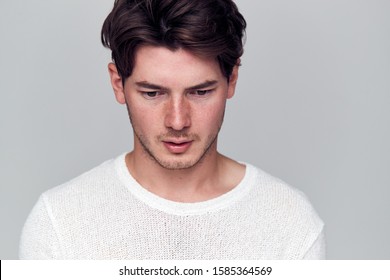 Studio Portrait Of Young Man With Guilty Expression Looking Down