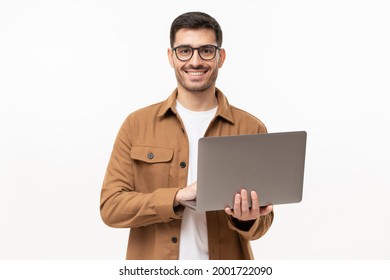 Studio Portrait Of Young Man Standing Holding Laptop And Looking At Camera With Happy Smile, Isolated On Gray