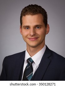 Studio Portrait Of Young Man In Suit And Tie On Gray Background, Head And Shoulders