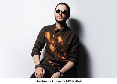 Studio Portrait Of Young Serious Man Wearing Round Sunglasses, White Background.