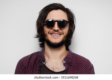 Studio Portrait Of Young Smiling Guy With Round Sunglasses On White Background.