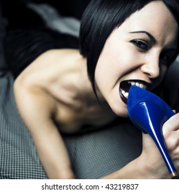 Studio Portrait Of The Young Woman Eating The Shoe