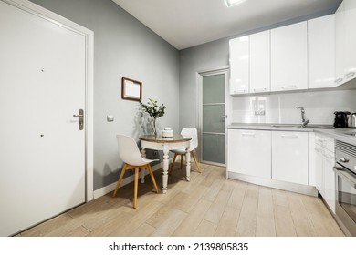 Studio With Round Dining Table And White Gloss Kitchen Cabinets With Gray Stone Countertop And Wooden Floorboards