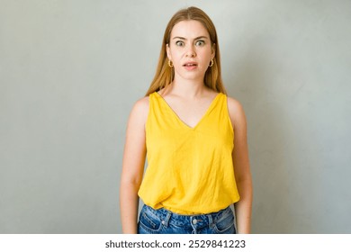 In a studio setting, a shocked expression is being made by a young woman with long blonde hair