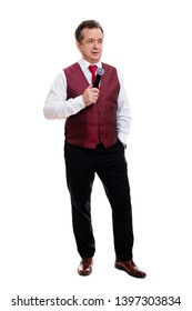 Studio Shoot. Successful Senior Man 55-60 Years Old. Male Stand In Beautiful Vest With Red Tie And White Shirt. Grinning Male Hold Microphone And Second Hand In Pocket. Isolated On White Background.