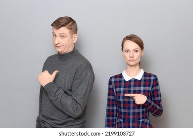 Studio Shot Of Adult Couple, Disappointed Man And Serious Focused Woman Are Pointing At Each Other. Concept Of Relationship, Interaction Between People, Gender Relations, Communication Issues