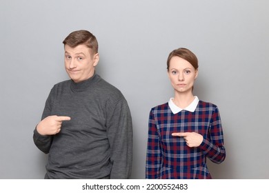 Studio Shot Of Adult Couple, Disappointed Man And Serious Focused Woman Are Pointing At Each Other. Concept Of Relationship, Interaction Between People, Gender Relations, Communication Issues