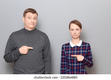 Studio Shot Of Adult Couple, Disappointed Man And Serious Focused Woman Are Pointing At Each Other. Concept Of Relationship, Interaction Between People, Gender Relations, Communication Issues