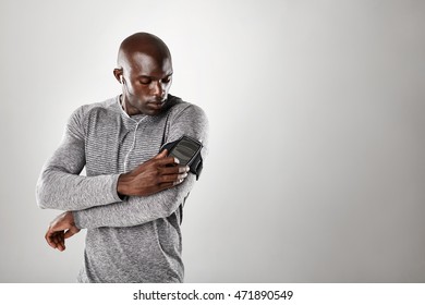 Studio shot of african muscular man listening to music on mobile phone. Fit young man against grey background with copy space. - Powered by Shutterstock