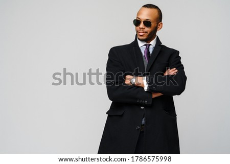 studio shot of a african-american businessman wearing coat over light grey background