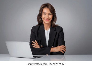 Studio shot of an attractive businesswoman using laptop for work. Smiling female sitting at isolated grey background. Copy space. - Shutterstock ID 2271757647