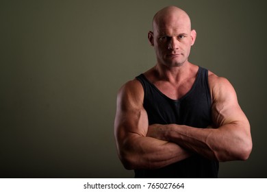 Studio shot of bald muscular man wearing tank top against colored background - Powered by Shutterstock