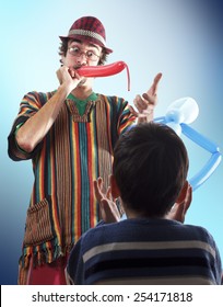 Studio Shot Of Balloon Twister Who Blowing Balloon And Entertaining Child In His Birthday Party.