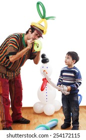 Studio Shot Of Balloon Twister Who Blowing Balloon And Entertaining Child In His Birthday Party.