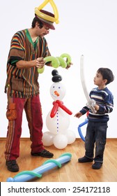 Studio Shot Of Balloon Twister Who Blowing Balloon And Entertaining Child In His Birthday Party.