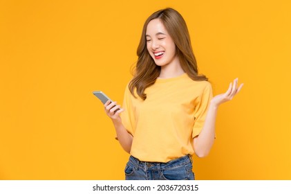 Studio Shot Of Beautiful Asian Woman Holding Smartphone And Smiling On Light Yellow Background