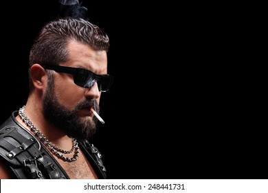Studio shot of a biker smoking a cigarette on black background