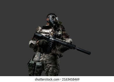 Studio Shot Of Black Military Man With Gas Mask Holding Rifle Isolated On Grey Background.