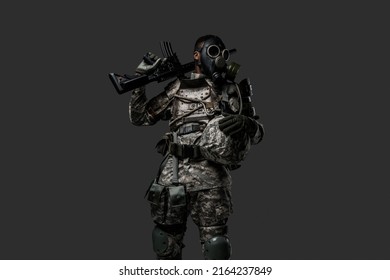 Studio Shot Of Black Military Man Holding Rifle On His Shoulder Isolated On Grey Background.