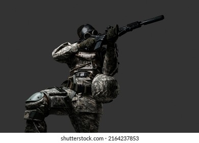 Studio Shot Of Black Military Man With Gas Mask Aiming Rifle Isolated On Grey Background.