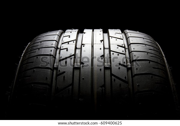 Studio shot of brand new car tire isolated on\
black background.