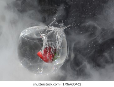 Studio Shot Capturing The Splash Of A Fresh Strawberry Dropping Into A Gin Goblet With Dry Ice Vapour