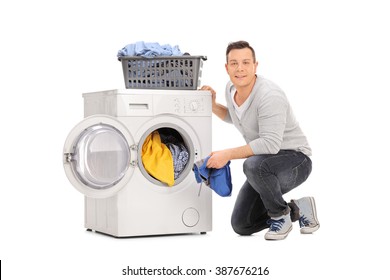 Studio Shot Of A Cheerful Young Man Doing Laundry And Looking At The Camera Isolated On White Background