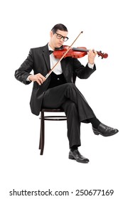 Studio Shot Of A Classical Musician Playing Violin Seated On Chair Isolated On White Background