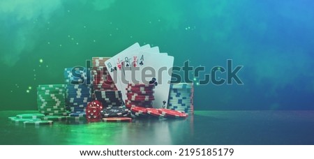 Studio shot composition of poker chips, dices and stack of playing cards on the desk with grunge texture over black background with smoke and glitter effect. 