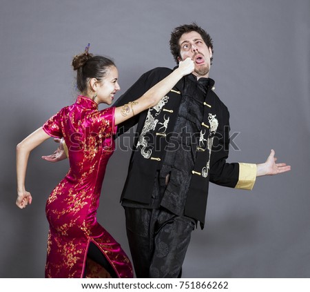 Studio shot of a couple in their early twenties, wearing traditional chinese clothing and being generaly very cute play-fighting together.