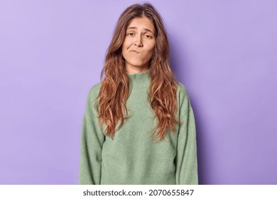 Studio shot of displeased bored woman purses lips and looks with uninterested expression wears casual jumper poses alone against purple background. Upset gloomy teenage girl tired of distance studying - Shutterstock ID 2070655847