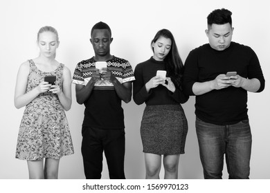 Studio shot of diverse group of multi ethnic friends using mobile phones together