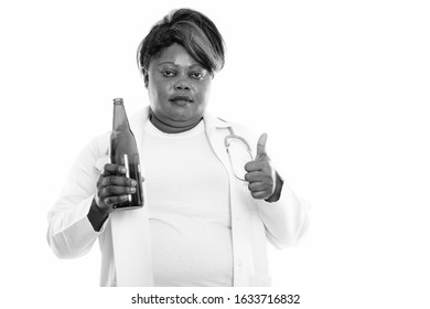 Studio Shot Of Fat Black African Woman Doctor Holding Bottle Of Beer While Giving Thumb Up