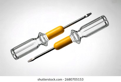 A studio shot features two flathead screwdrivers angled against a clean white background. Their handles are made of clear, fluted glass, with bright yellow collars.