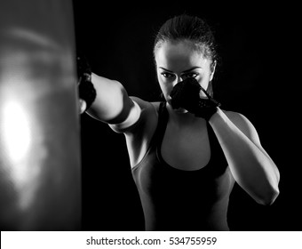 Studio Shot Of Female Boxer Punching A Boxing Bag, Black And White.