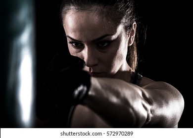 Studio Shot Of Female Boxer Punching A Boxing Bag.