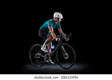 Studio Shot Of Female Cyclist, Young Woman On Road Bike Bicycle Riding Isolated On Black Studio Background. Concept Of Sport, Action, Motion, Speed, Race. Side View