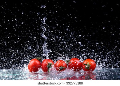 Studio Shot With Freeze Motion Of Cherry Tomatoes In Water Splash On Black Background