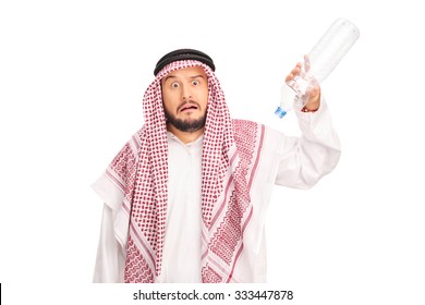 Studio Shot Of A Frightened Arab Holding An Empty Plastic Bottle With No Water In It Isolated On White Background