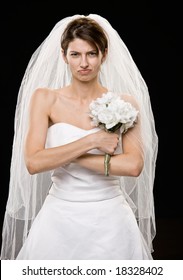 Studio shot of frowning young bride in wedding dress and veil