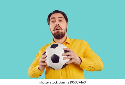 Studio Shot Of Funny Inexperienced Football Player. Funny Shy Guy Not Ready For The Game. Portrait Of Young Man In Yellow Shirt Holding Soccer Ball And Looking At Camera With Scared Facial