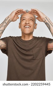 Studio Shot Of A Gorgeous Multiracial Man In His 50's Looking Up And Smiling On A White Seamless.