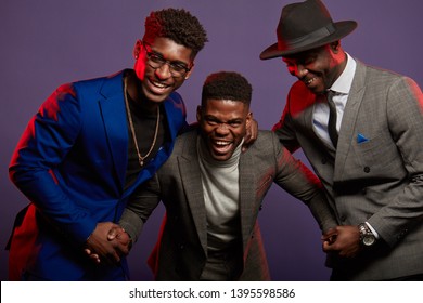 Studio shot of group of African male young adult friends wearing smart suits having fun and laughing over dark violet background - Powered by Shutterstock