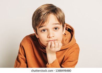 Studio Shot Of Handsome 10 Year Old Boy With Blond Hair, Wearing Brown Hoody, Posing On White Background