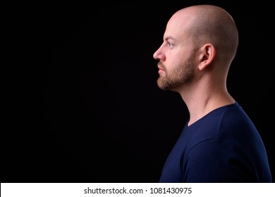 Studio Shot Of Handsome Bald Bearded Man Against Black Background