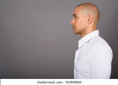 Studio shot of handsome bald businessman against gray background