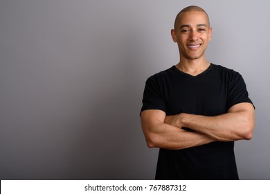 Studio Shot Of Handsome Bald Man Wearing Black Shirt Against Gray Background